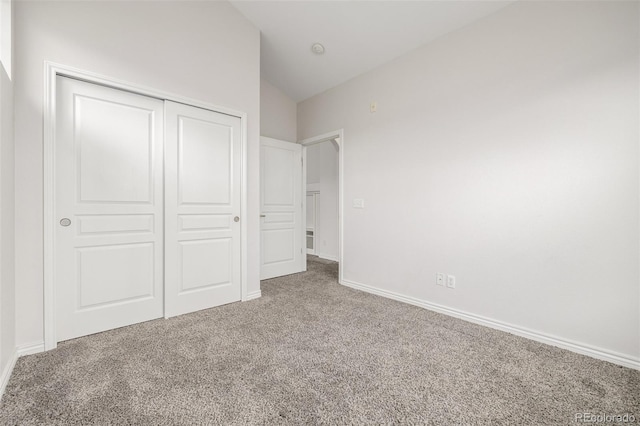 unfurnished bedroom with a closet, lofted ceiling, and carpet flooring