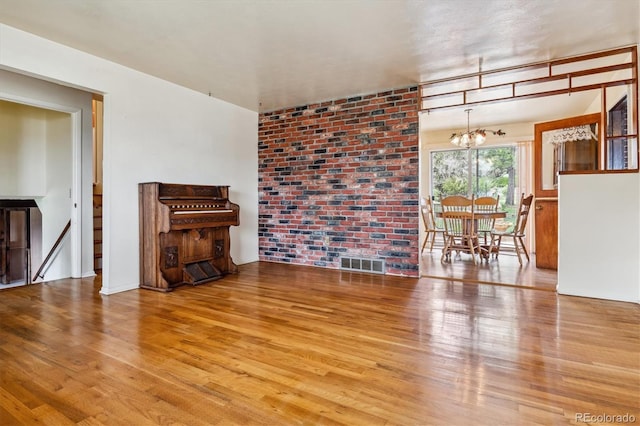 unfurnished living room featuring a chandelier, visible vents, and wood finished floors