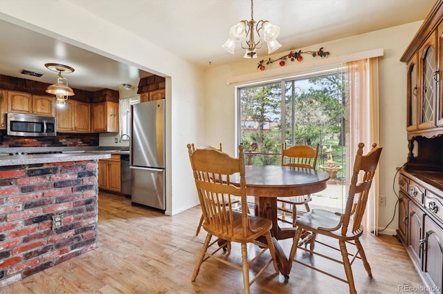 dining area featuring light wood finished floors, visible vents, baseboards, and a notable chandelier