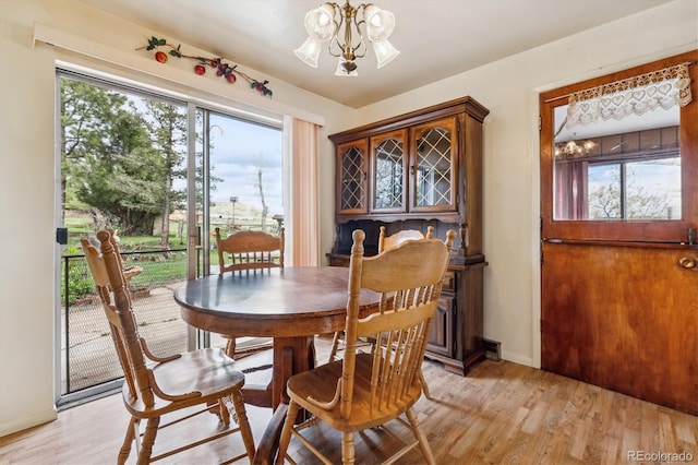 dining space with an inviting chandelier, a wealth of natural light, baseboards, and light wood-type flooring