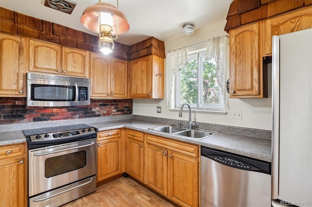 kitchen featuring stainless steel appliances, light wood-style flooring, decorative backsplash, and a sink