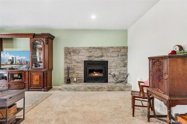 living area with carpet floors and a stone fireplace