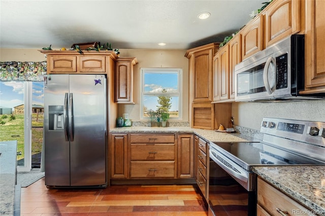 kitchen with recessed lighting, light stone countertops, light wood finished floors, and stainless steel appliances