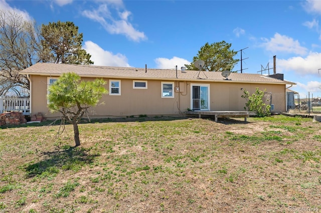 back of house featuring a lawn and fence
