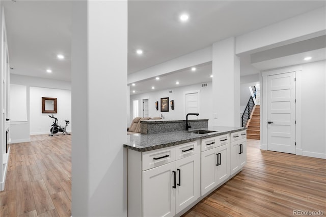 12215 Viewpoint Dr, Lakewood, CO 80401 - kitchen featuring recessed lighting, dark stone countertops, light wood-style floors, white cabinetry, and a sink