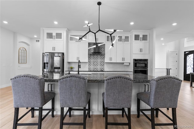 12215 Viewpoint Dr, Lakewood, CO 80401 - kitchen featuring a breakfast bar, wall chimney range hood, stainless steel refrigerator with ice dispenser, and dobule oven black
