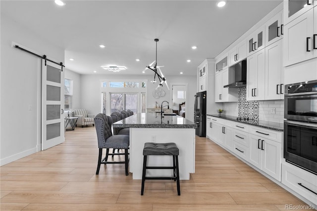 12215 Viewpoint Dr, Lakewood, CO 80401 - kitchen with black appliances, a sink, a kitchen breakfast bar, a barn door, and wall chimney exhaust hood