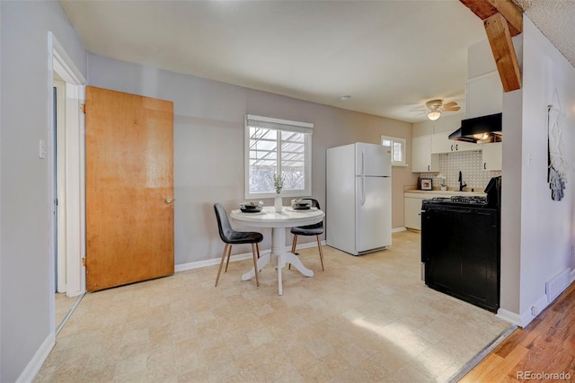 2601 Cooper Ave, Colorado Springs, CO 80907 - kitchen featuring freestanding refrigerator, black gas stove, under cabinet range hood, white cabinets, and a ceiling fan