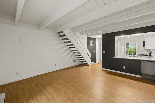 3110 Van Teylingen Dr Unit C, Colorado Springs, CO 80917 - unfurnished living room featuring stairs, light wood finished floors, a sink, baseboards, and wood ceiling with exposed beams