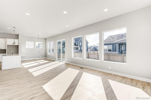 unfurnished living room featuring sink and light hardwood / wood-style floors