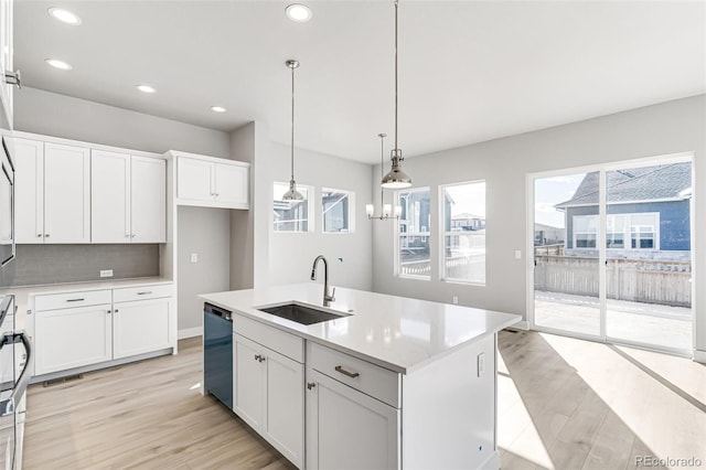 kitchen featuring a kitchen island with sink, decorative light fixtures, sink, and white cabinetry