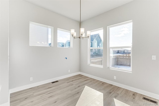 unfurnished dining area with a notable chandelier and light hardwood / wood-style floors