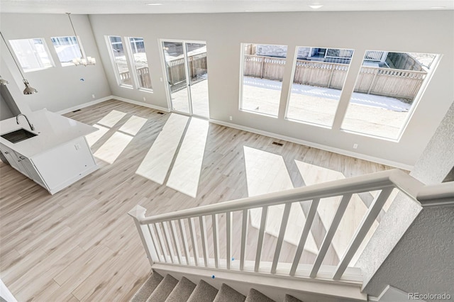 staircase with a notable chandelier, hardwood / wood-style flooring, and vaulted ceiling