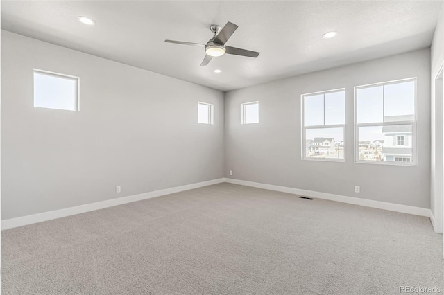 carpeted spare room featuring ceiling fan and a wealth of natural light