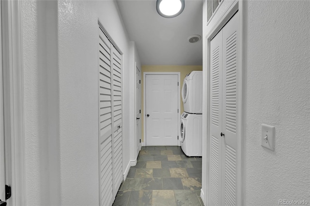 243 Cherokee Ct, Brighton, CO 80603 - laundry area with estacked washer and dryer, dark stone finish flooring, and baseboards