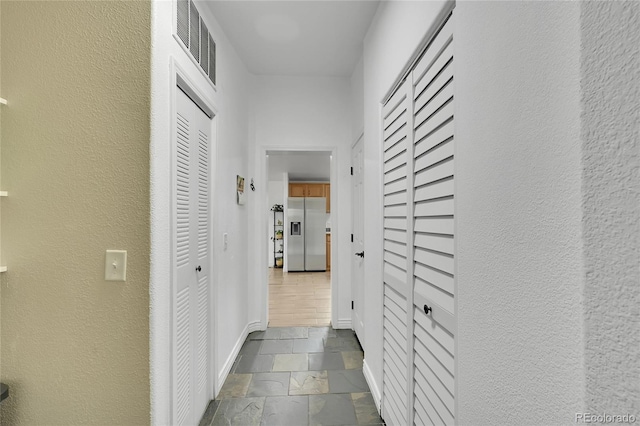 243 Cherokee Ct, Brighton, CO 80603 - hallway featuring stone tile floors, a textured wall, and baseboards