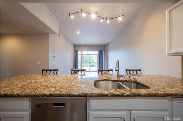 kitchen with white cabinetry, stainless steel dishwasher, sink, and dark stone counters