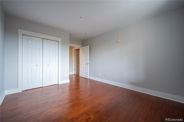 unfurnished bedroom featuring a closet, wood finished floors, and baseboards