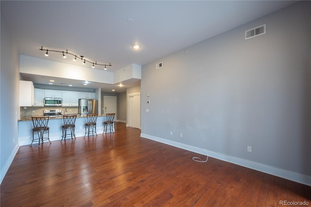 living room featuring dark wood-style flooring, visible vents, and baseboards