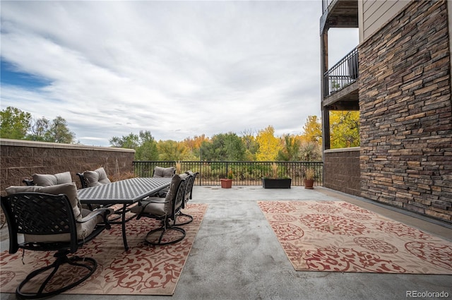 view of patio with a balcony and outdoor dining space