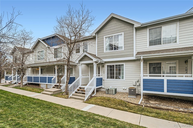 multi unit property featuring a porch, a front yard, and cooling unit