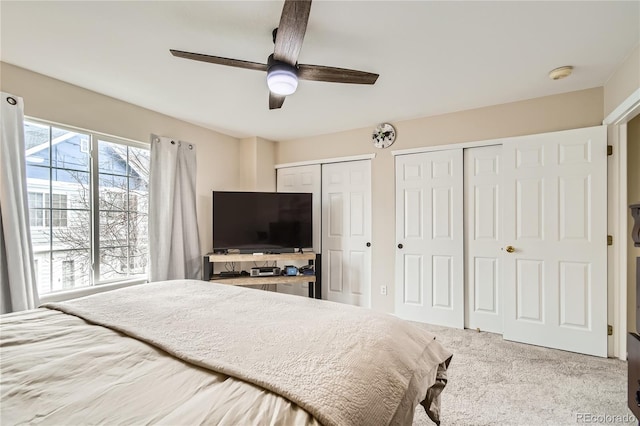 carpeted bedroom featuring ceiling fan and multiple closets