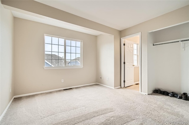 unfurnished bedroom with light carpet, ensuite bath, and a closet