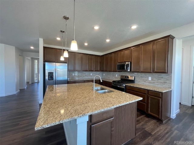 kitchen with decorative backsplash, a spacious island, appliances with stainless steel finishes, dark wood-style flooring, and a sink