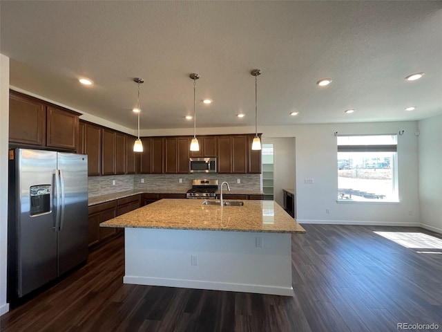 kitchen with light stone countertops, dark wood-style flooring, stainless steel appliances, and a sink