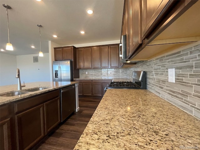 kitchen with dark wood-style floors, light stone counters, a sink, stainless steel appliances, and backsplash