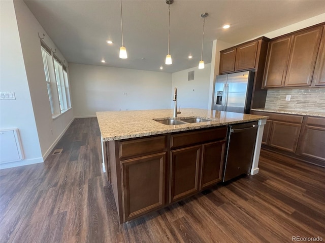 kitchen featuring dark wood-type flooring, appliances with stainless steel finishes, an island with sink, and a sink