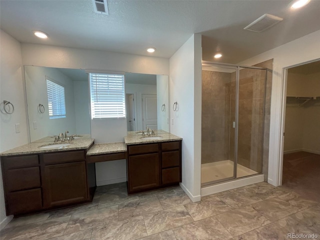 bathroom with a shower stall, visible vents, two vanities, and a sink