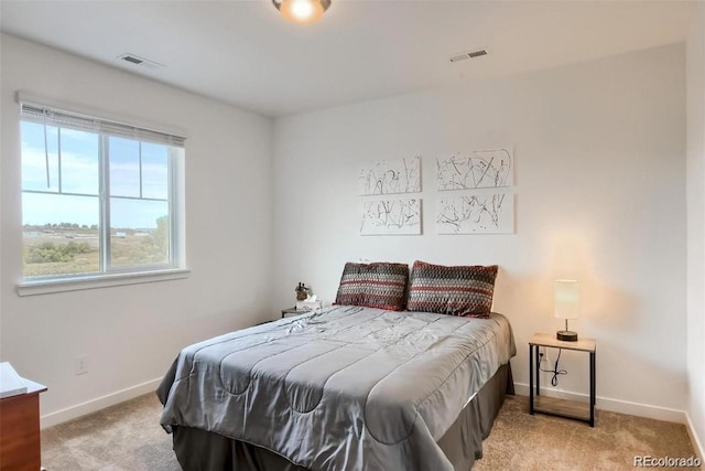 bedroom featuring baseboards, visible vents, and light colored carpet