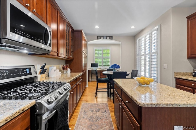5301 Clovervale Cir, Highlands Ranch, CO 80130 - kitchen featuring stainless steel appliances, light wood-style floors, a center island, glass insert cabinets, and recessed lighting