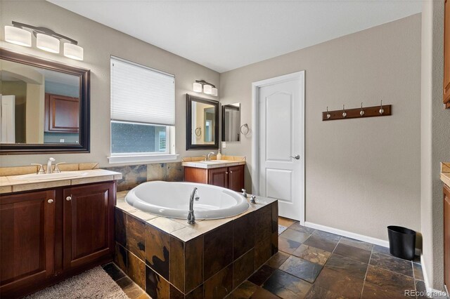 5301 Clovervale Cir, Highlands Ranch, CO 80130 - full bathroom featuring two vanities, a garden tub, baseboards, and stone tile floors