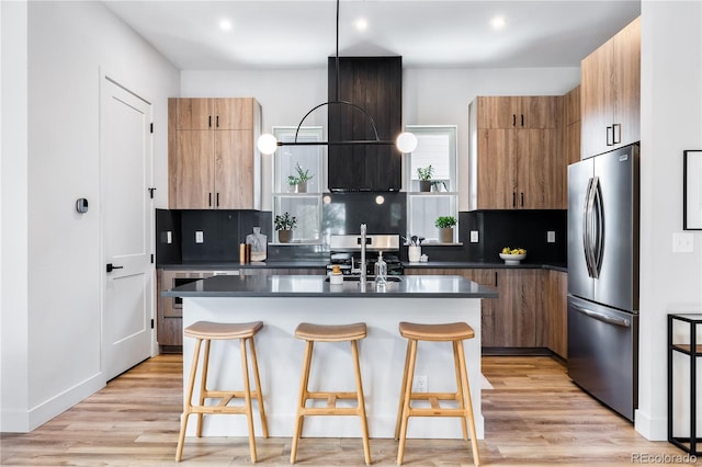 kitchen with light hardwood / wood-style floors, a kitchen island, a breakfast bar, decorative backsplash, and stainless steel refrigerator