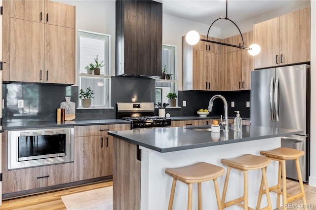 kitchen with a kitchen bar, a center island with sink, stainless steel appliances, tasteful backsplash, and sink