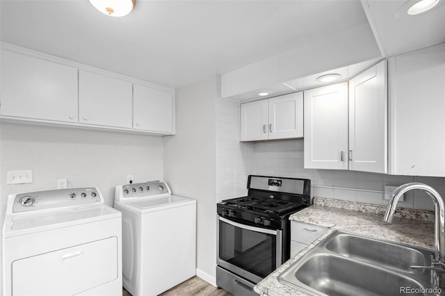 4785 Carr St, Wheat Ridge, CO 80033 - kitchen featuring stainless steel range with gas cooktop, washer and clothes dryer, white cabinets, and tasteful backsplash