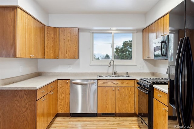 kitchen featuring light hardwood / wood-style floors, black appliances, and sink