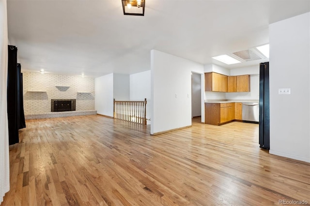 unfurnished living room featuring a fireplace, brick wall, and light hardwood / wood-style flooring