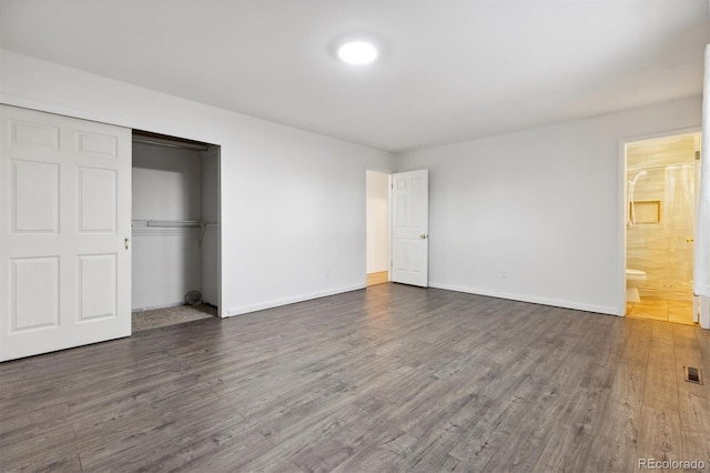 unfurnished bedroom with dark hardwood / wood-style flooring, ensuite bath, and a closet