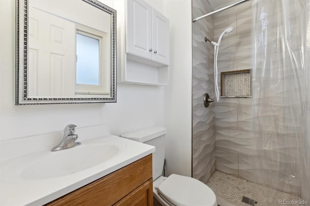 bathroom featuring vanity, toilet, and tiled shower