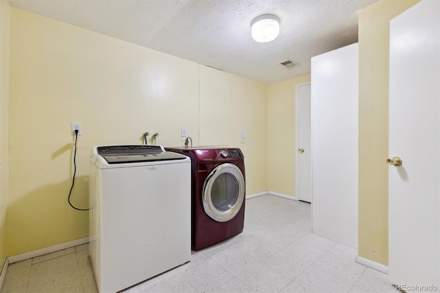 laundry room featuring washer and clothes dryer and a textured ceiling