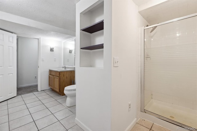 bathroom with tile patterned floors, vanity, a textured ceiling, toilet, and a shower with shower door