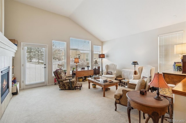 living area featuring high vaulted ceiling, carpet, a glass covered fireplace, and a wealth of natural light