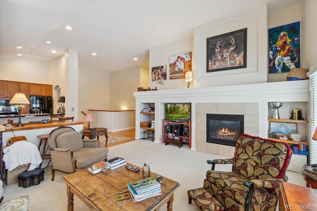 carpeted living room with a tile fireplace and vaulted ceiling