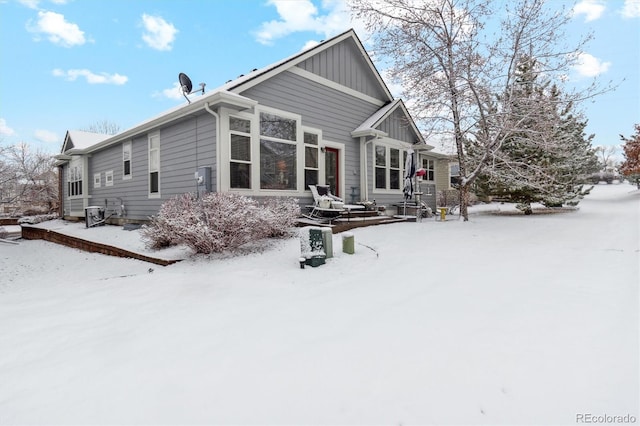 snow covered house featuring board and batten siding and central air condition unit