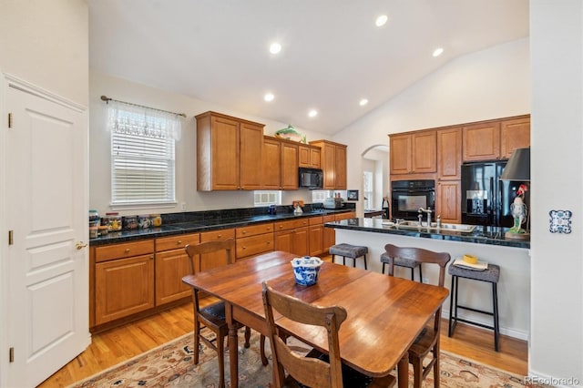 kitchen with brown cabinetry, dark countertops, and black appliances