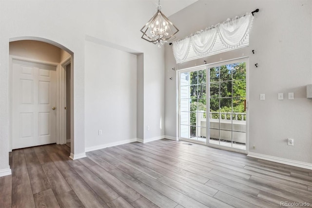 empty room featuring an inviting chandelier and hardwood / wood-style floors