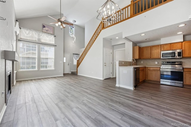 kitchen with high vaulted ceiling, light wood-type flooring, appliances with stainless steel finishes, and sink